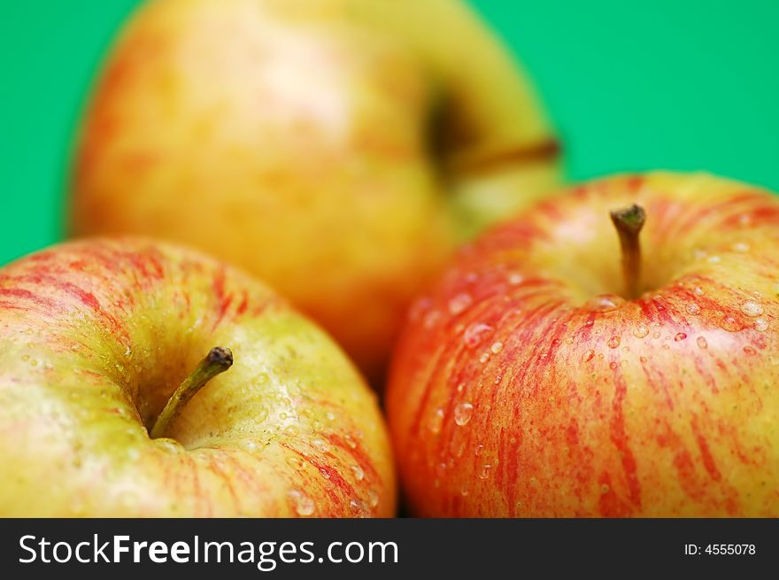 Three apples with drops on a green background