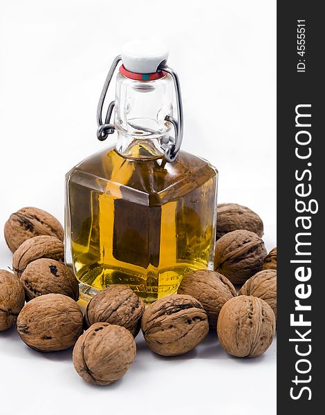 Bottle of spirit with nuts on white background