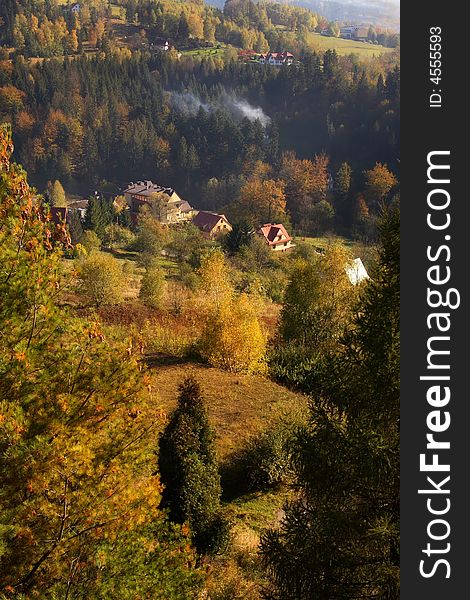 Colorful autumn trees in mountains and few houses. Colorful autumn trees in mountains and few houses