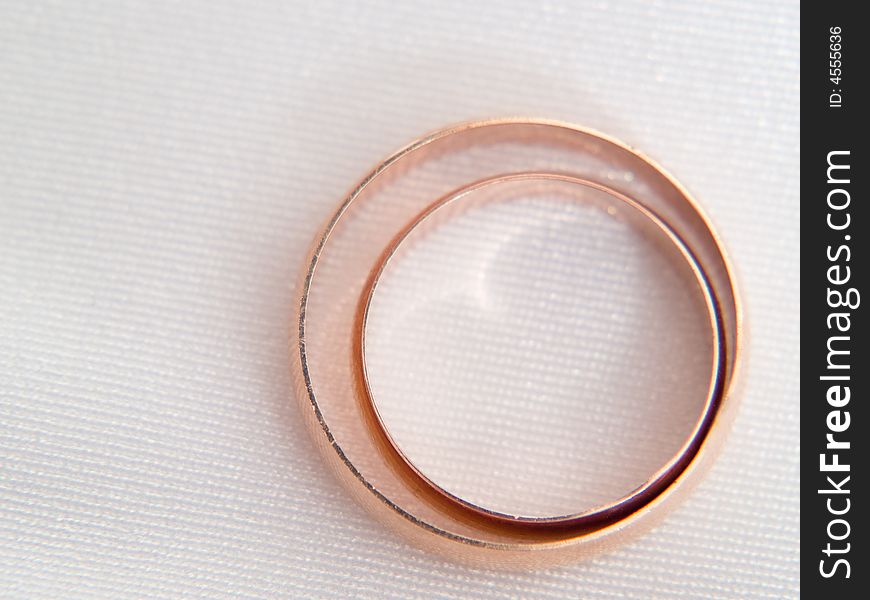 Closeup of wedding rings on a textured white background.