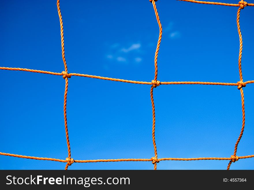 A capture of an orange soccer net in a clear blue sky day. A capture of an orange soccer net in a clear blue sky day