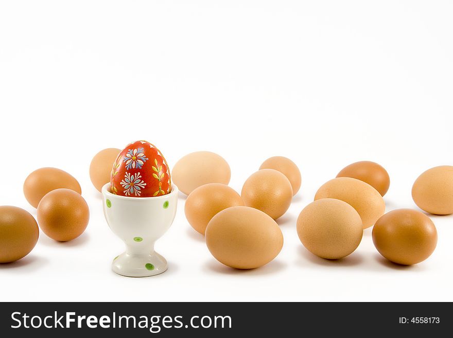 The hand painted red egg in egg-cup among natural eggs. The hand painted red egg in egg-cup among natural eggs