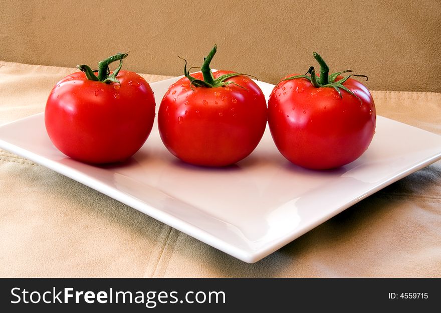 3 Red Vine Ripened Tomatoes On A White Plate.