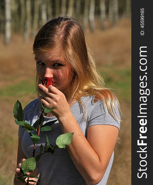 Beautiful young woman holding in hand a red rose