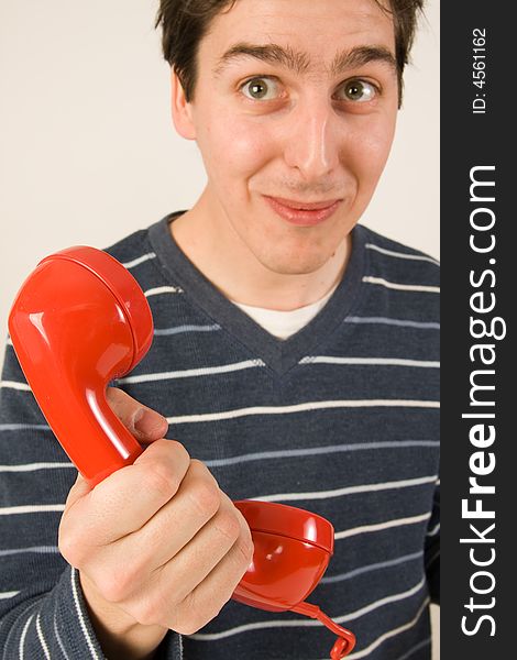 Young funny man holding red telephone receiver