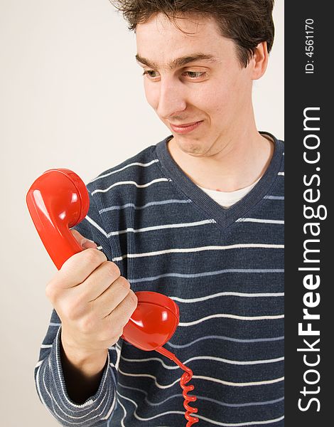 Young funny man holding red telephone receiver