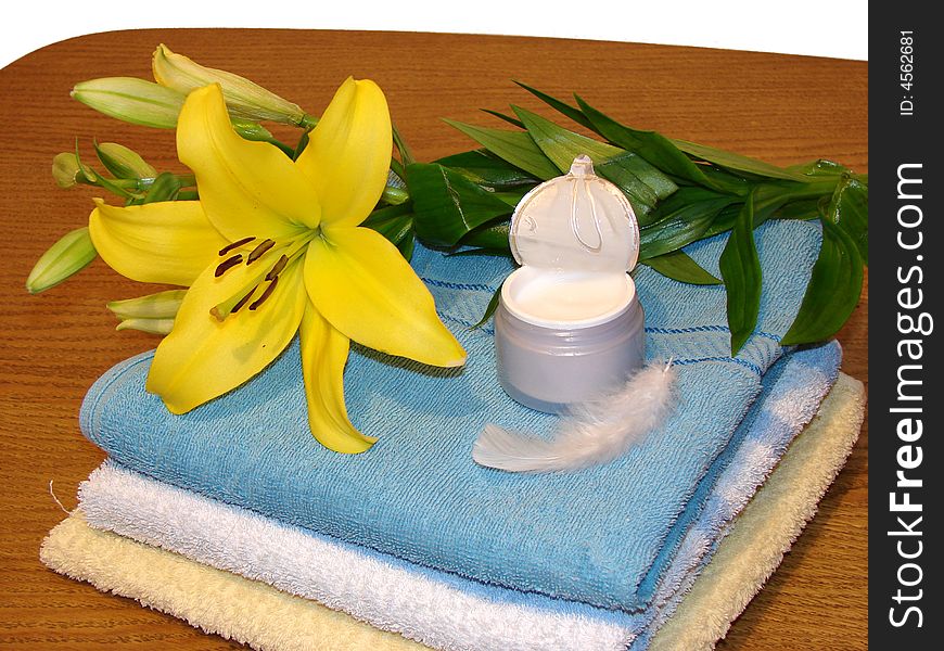 Towels, yellow flower, cream, and white feather as a concept of beauty, massage and alternative medicine.