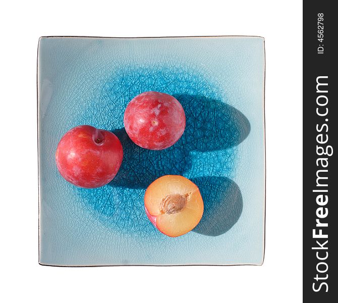 Plums on blue square plate, isolated