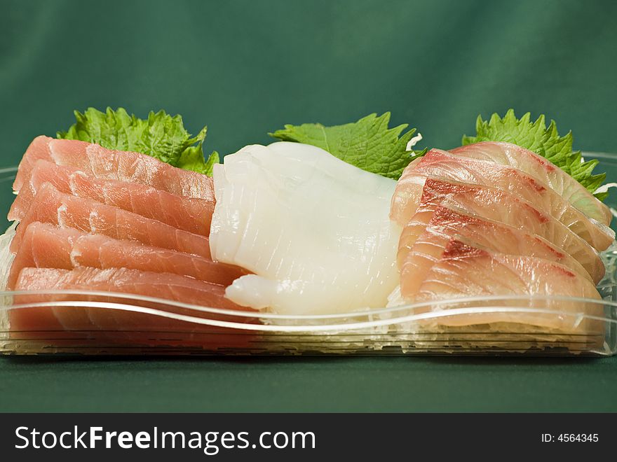 Plate of traditional Japanese food called sasimi; different raw fish slices lay on cut vegetables; this is macro-image sharp focus is on central part. Plate of traditional Japanese food called sasimi; different raw fish slices lay on cut vegetables; this is macro-image sharp focus is on central part