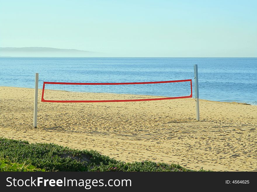 A beach volleyball net on the beach at the ocean