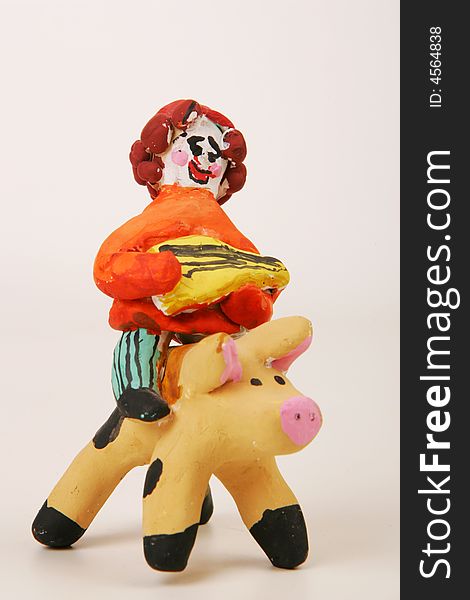 A painted clay figure of a merry musician riding a pig. A painted clay figure of a merry musician riding a pig