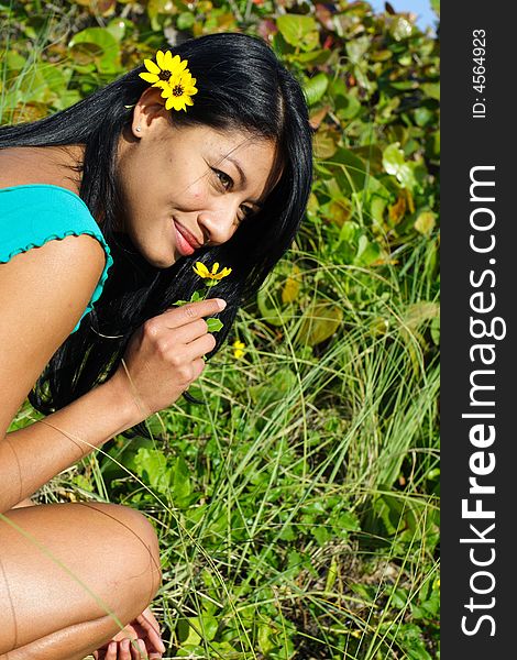 Woman smelling a flower with greenery in the background