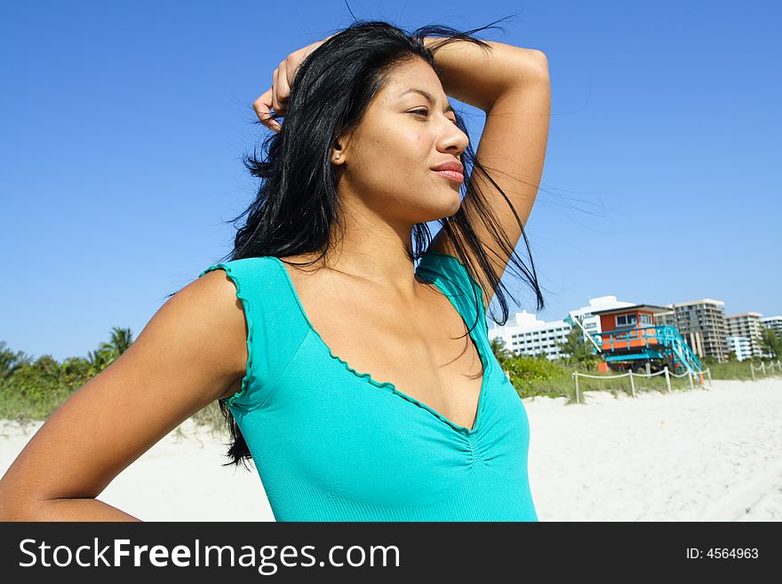 Woman at the beach with her hand on her head.