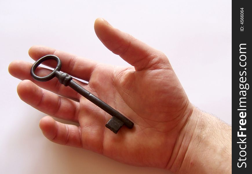 Right hand holding a vintage key on white background