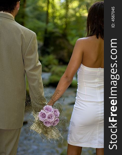 Couple seen from back holding a bouquet. Couple seen from back holding a bouquet