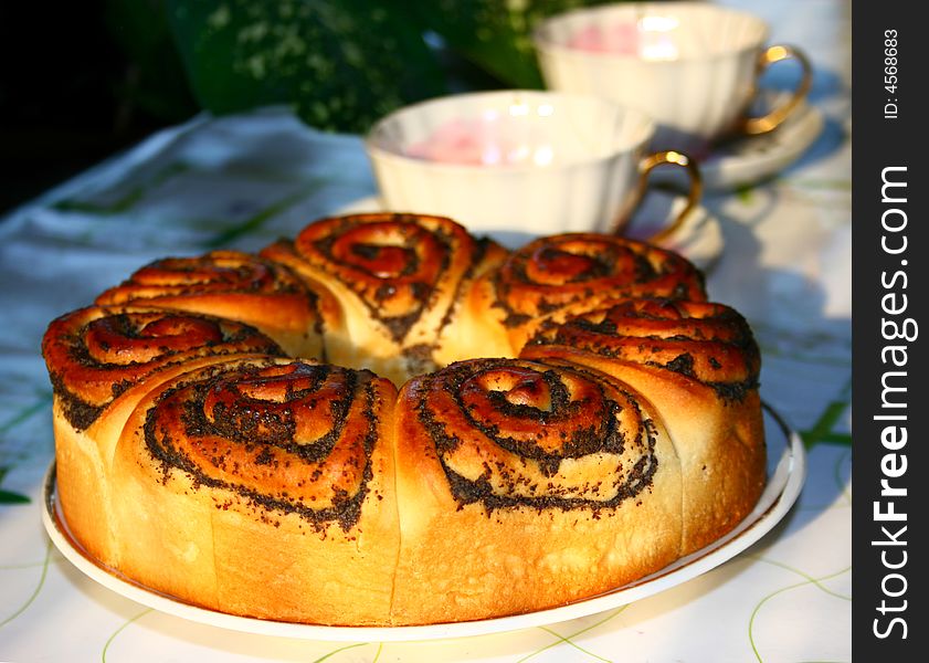 Brown pie and cups on table in evening light. Brown pie and cups on table in evening light