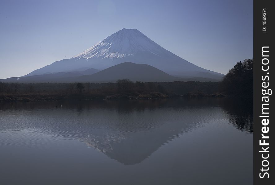 Winter view of Mount Fuji with mist and reflections in a lake. Winter view of Mount Fuji with mist and reflections in a lake