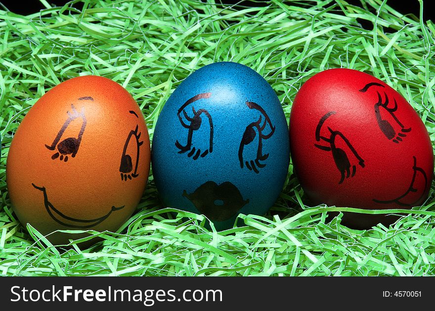 Colored eggs are standing with green on the black background. Colored eggs are standing with green on the black background
