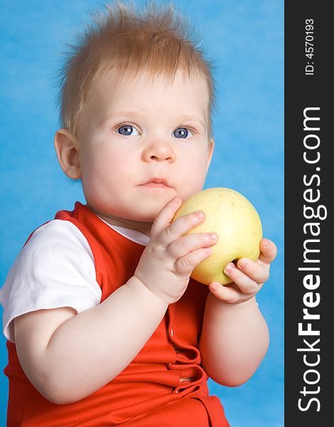 Baby boy eating an apple isolated on a blue background