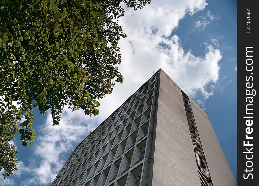 A tall building from low angle with blue sky and foliage. A tall building from low angle with blue sky and foliage