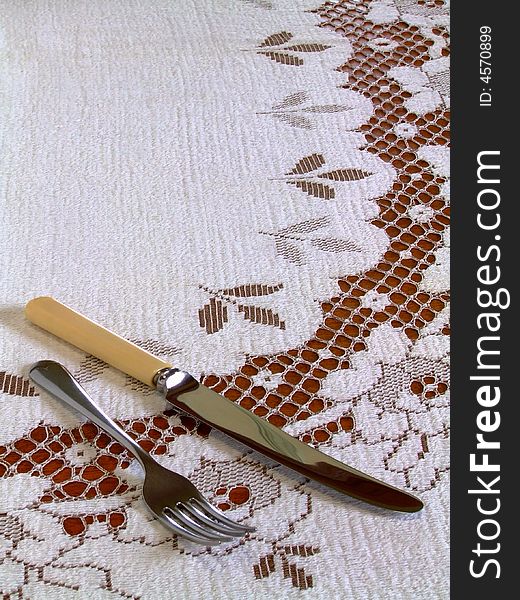 A fork and a bone-handled knife lying on a lace-work tablecloth. A fork and a bone-handled knife lying on a lace-work tablecloth.