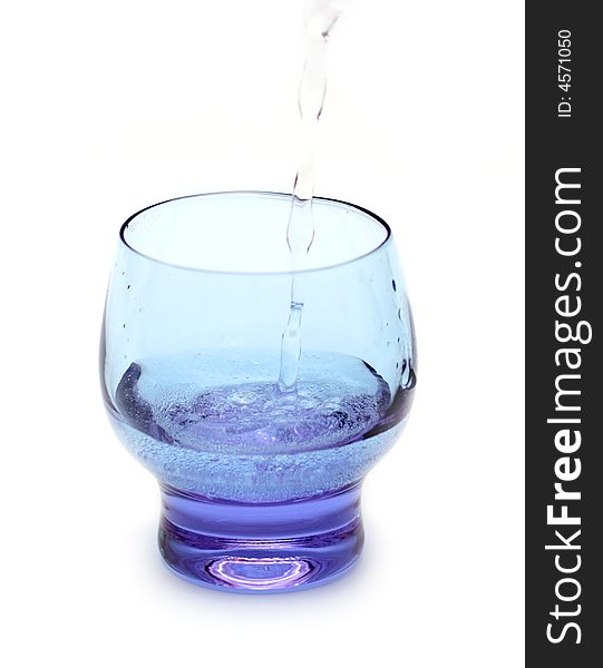 Stream of water falling into purple glass isolated on white. Stream of water falling into purple glass isolated on white