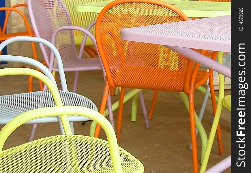 An arrangement of colorful cafe tables outside in the sun.