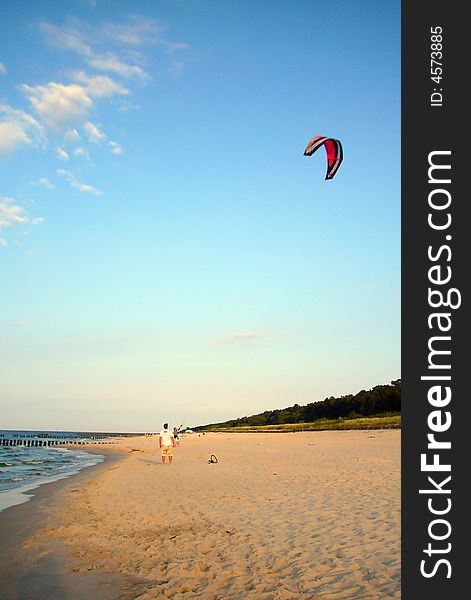 Kite-boarder trays to prepare his kite on a beach. Kite-boarder trays to prepare his kite on a beach.