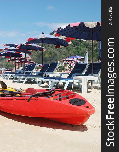 Red sea kayak on the beach surrounded by beach umbrellas.