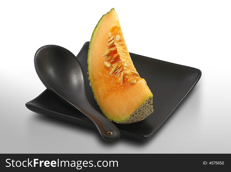 Fresh, ripe melon served on stylish, black plate, on white, isolated. Fresh, ripe melon served on stylish, black plate, on white, isolated