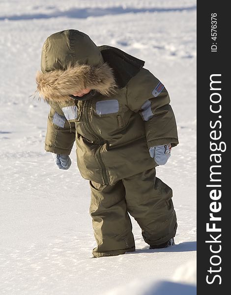 Little boy in a green arctic jacket with a collar et on to snow at the frozen lake. Little boy in a green arctic jacket with a collar et on to snow at the frozen lake