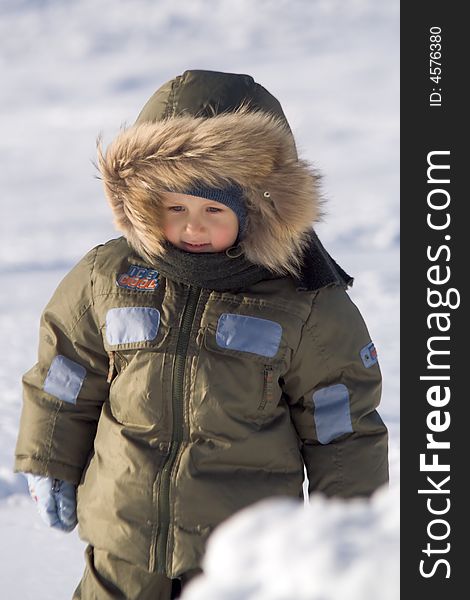 Little boy in a green arctic jacket with a collar et on to snow at the frozen lake. Little boy in a green arctic jacket with a collar et on to snow at the frozen lake