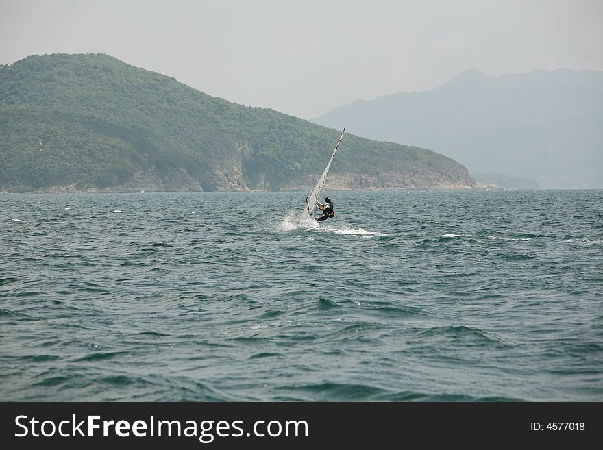 A single yatch across calm blue waters. A single yatch across calm blue waters