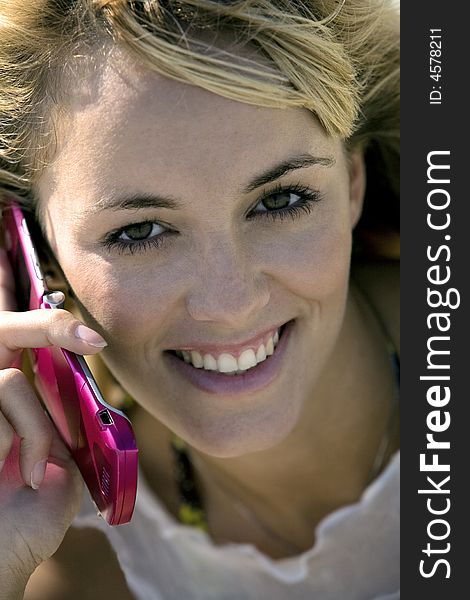 Attractive smiling blonde woman holds a mobile phone looking straight in the camera. Attractive smiling blonde woman holds a mobile phone looking straight in the camera