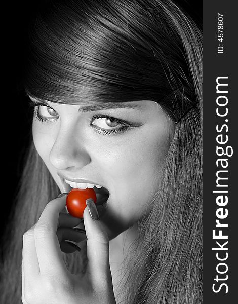 Beautiful young woman biting a tomato. Beautiful young woman biting a tomato