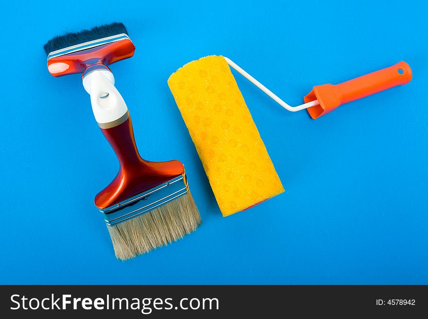 Paint brushes and paint roller on blue background. Paint brushes and paint roller on blue background