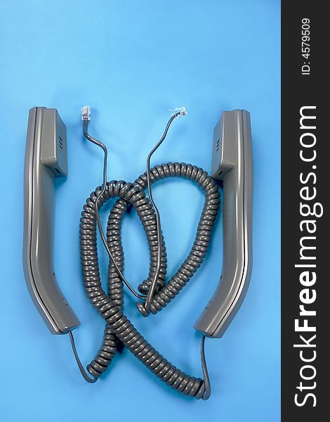 Two unplugged phone handsets on blue background. Two unplugged phone handsets on blue background