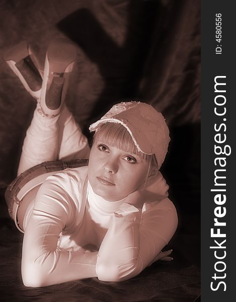 The girl in a white cap lays on a floor. Sepia. The girl in a white cap lays on a floor. Sepia