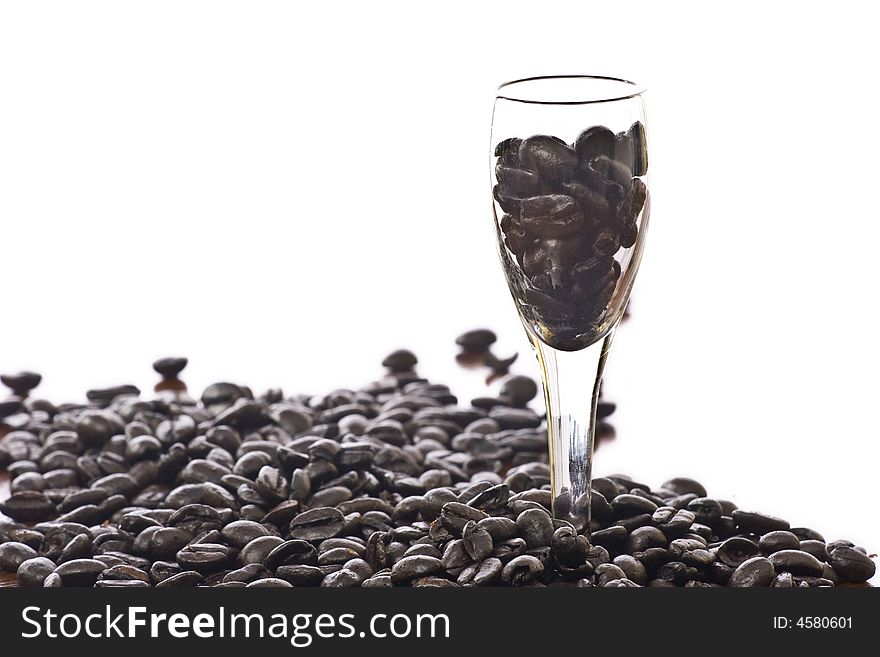 Spilled coffee beans isolated over white with shot glass. Spilled coffee beans isolated over white with shot glass