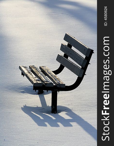 Isolated park bench in winter with long casted shadows. Isolated park bench in winter with long casted shadows.