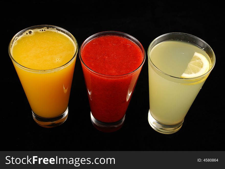 Three cups of juice isolated by black background