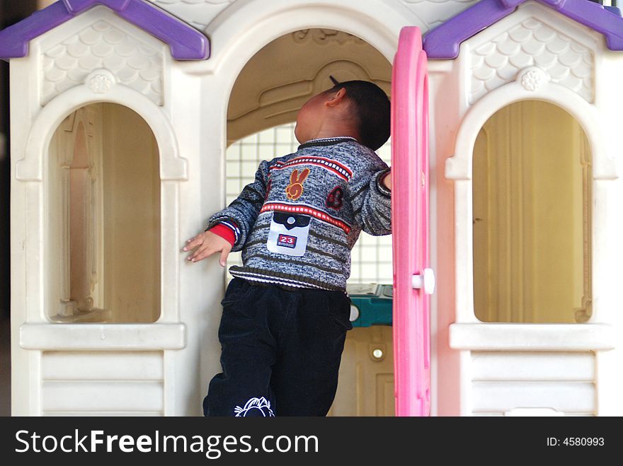 A naughty Chinese boy play happily in the kindergarten doll house, colorful plastic doll house. A naughty Chinese boy play happily in the kindergarten doll house, colorful plastic doll house