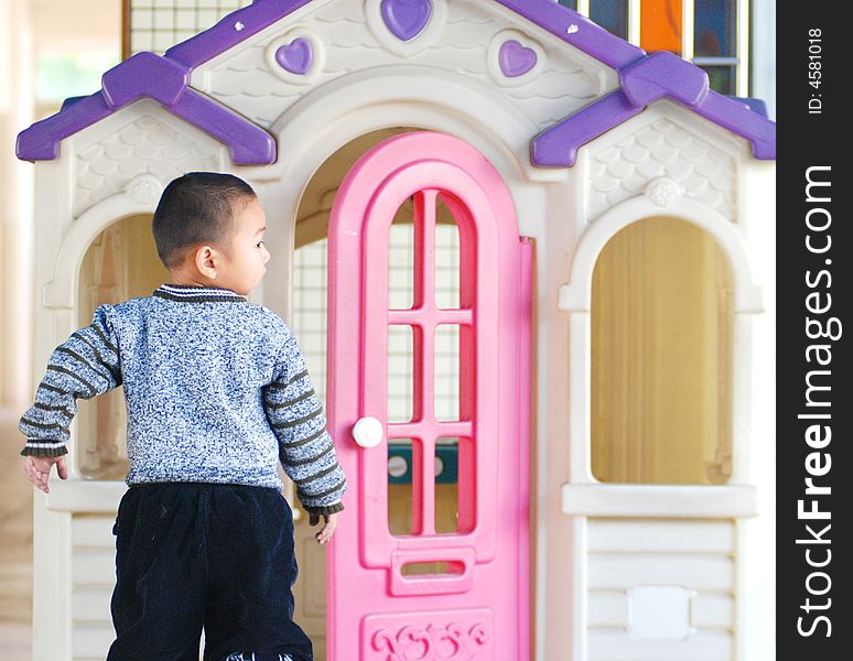 A Chinese kid of three years old play before a colorful plastic doll house. A Chinese kid of three years old play before a colorful plastic doll house.