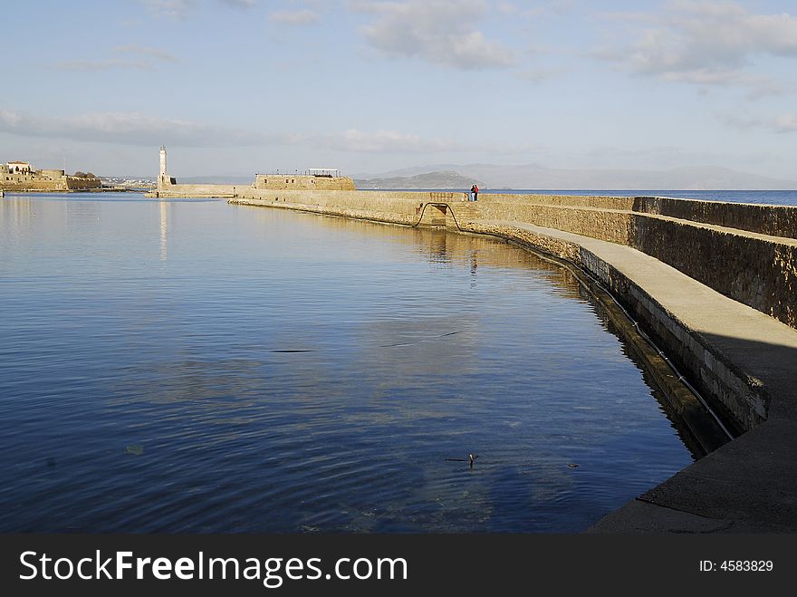 surrounding wall of the old harbour in Chania and its light tower. surrounding wall of the old harbour in Chania and its light tower