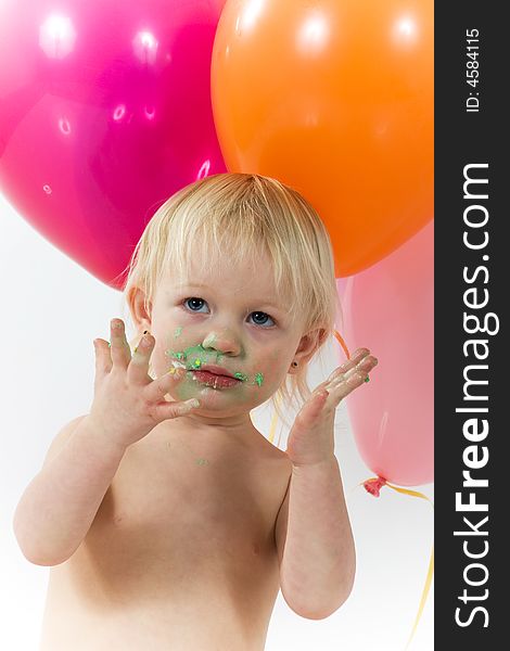 A little girls shows us her messy face and hands with balloons in the background. A little girls shows us her messy face and hands with balloons in the background