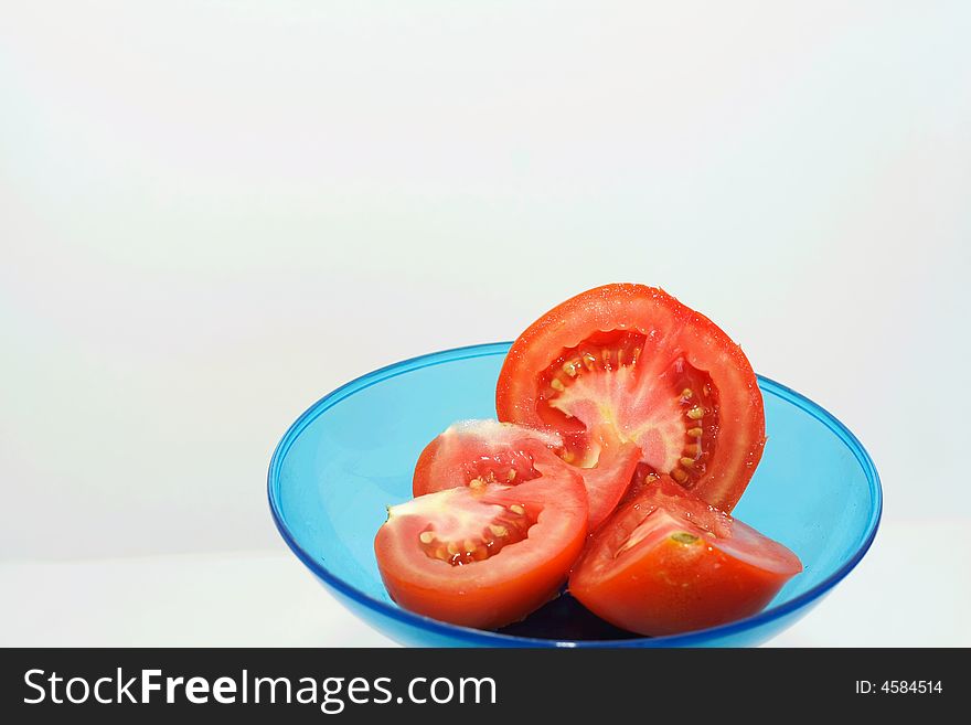 Close up of fresh tomatoes and slices on blue plate isolated on white background