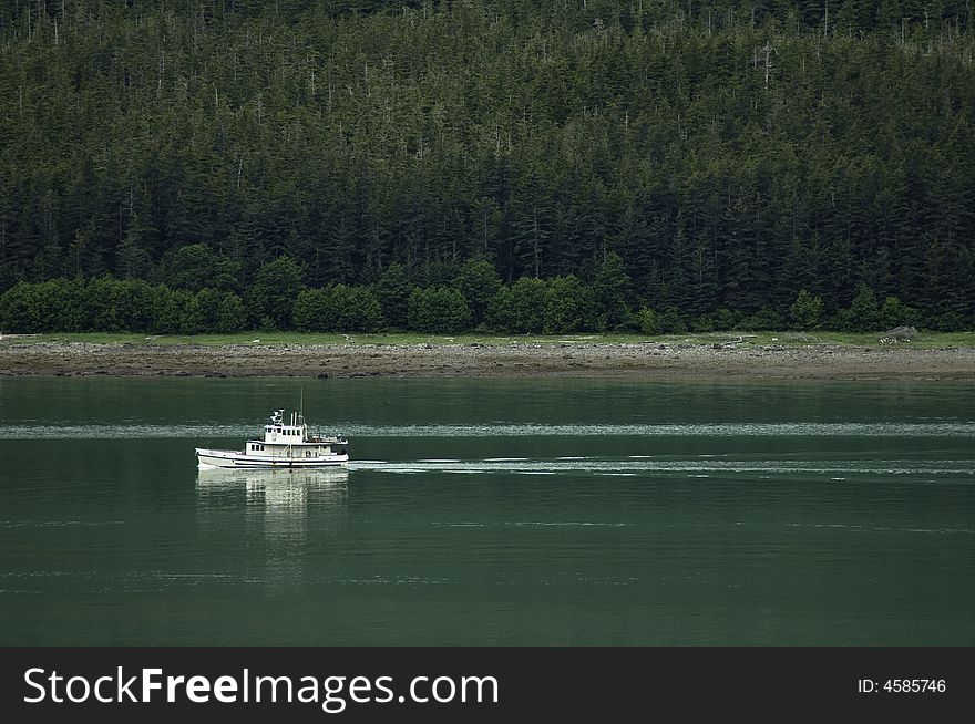 A fishing boat slips through an Alaskan fjord. A fishing boat slips through an Alaskan fjord
