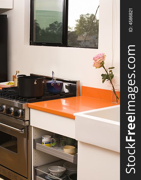 Home interior view of a kitchen counter and metal stove. The stove has a black stock pot on the range and some food ingredients to the side. Home interior view of a kitchen counter and metal stove. The stove has a black stock pot on the range and some food ingredients to the side.