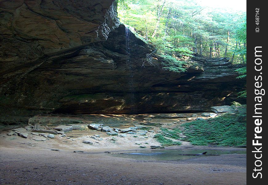 Dramatic rock overhang with small 50 foot waterfall. Dramatic rock overhang with small 50 foot waterfall