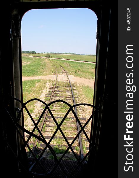 Railway tracks stretching off around a bend from the door of the last car. Railway tracks stretching off around a bend from the door of the last car